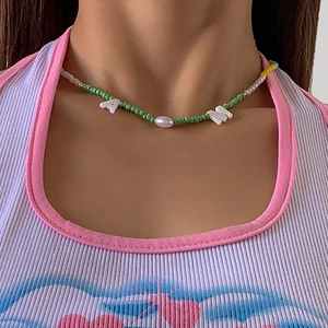 Detail van de handgemaakte groene boheemse kralenketting met witte alfabetische bedeltjes