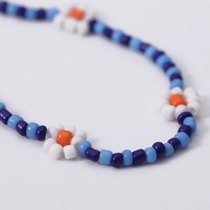 Detail van de boheemse kleurrijke madeliefjesketting met blauwe en paarse harskralen