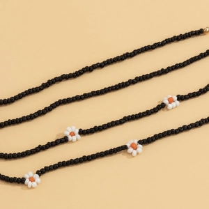 Detail shot of bohemian handmade black seed bead body chain with tiny white daisy flowers