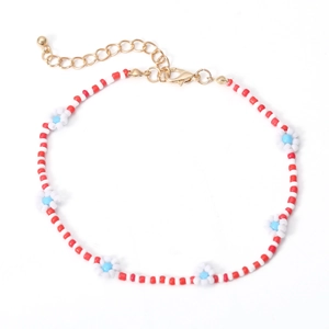 Detailweergave van de Bohemian madeliefjesketting met rode kralen en gouden sluiting