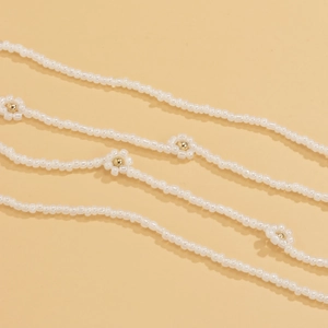 Detail of bohemian daisy waist chain featuring white beads and golden floral accents