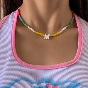 Detail van kleurrijke kralen choker halsketting met een witte hoofdletter M hanger bedel