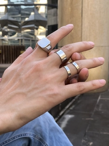 Nahaufnahme von minimalistischen silbernen Siegelringen und Bandringen an einer Männerhand