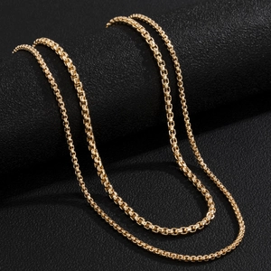 Dettaglio di una collana a catena box dorata su un supporto in pelle nera
