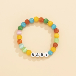 Dettaglio del bracciale di perle occhio di gatto colorate con lettere BABY bianche