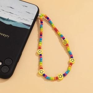 Detailed view of colorful macaron beaded phone charm with yellow smiley faces on yellow background