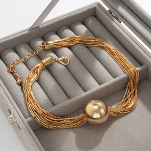 Gelaagde gouden ketting met een grote gepolijste geometrische bolvormige hanger