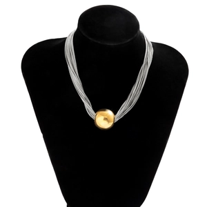 Détail de chaînes serpent argentées à plusieurs rangs avec pendentif boule dorée polie