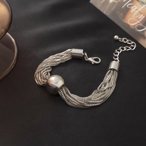 Détail d'un bracelet multi-rangs en maille miroir argentée avec une grande bille polie