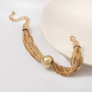 Détail d'un bracelet doré multi-rangs avec une grande perle centrale et fermoir mousqueton