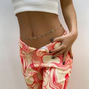 Detail showing a colorful heart charm waist chain on model in Y2K bohemian style