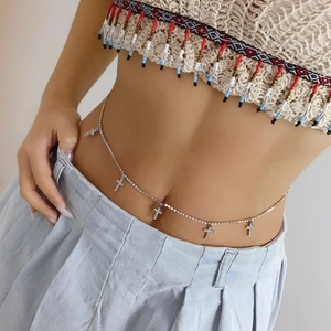 Detail of rhinestone waist chain featuring five sparkling cross pendants on a model