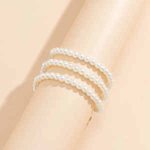Gros plan sur un bracelet à trois rangées de perles d'imitation au fini brillant