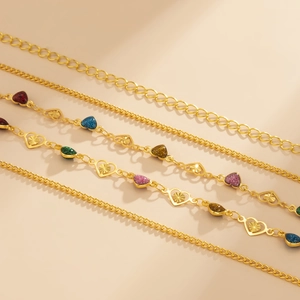 Detail of gold body chain featuring multicolored heart charms and hollow metal links