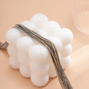 Détail macro de chaînes en argent multicouches montrant la texture et le drapé métallique