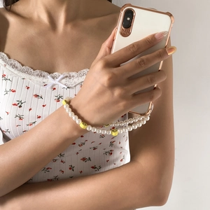 Detailed shot of white faux pearl phone strap with yellow smiley beads on a smartphone