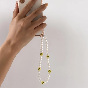 Detail of beaded phone strap with white pearls and yellow smiley face charms