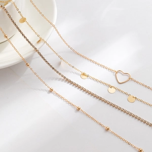 Détails d'un ensemble de chaînes dorées avec pendentifs en cœur, paillettes et strass brillants