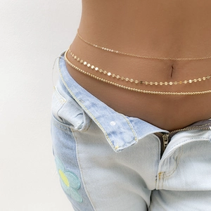 Detailed shot of three-layer gold sequin and bead belly chain worn with denim jeans