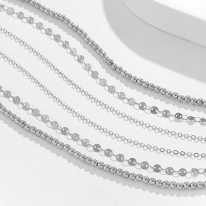 Detailed view of silver sequin waist chains with geometric bead and cross chain textures