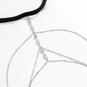 Detail van zilveren dijketting met sterrensteentjes en zwarte elastische bandriem