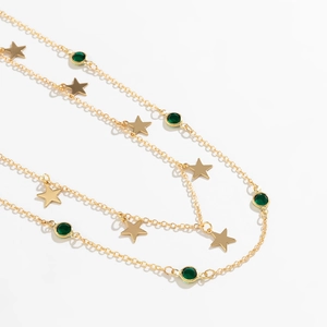Vue détaillée de la ceinture chaîne dorée avec breloques étoiles et cristaux verts