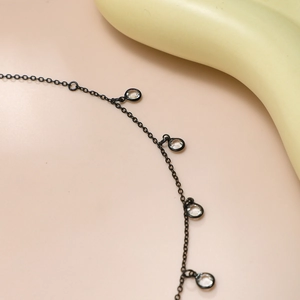 Détail d'une ceinture chaîne en métal noir minimaliste avec des cristaux sertis clos