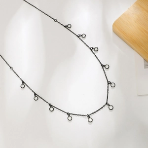 Détail de la ceinture chaîne en métal noir avec pendentifs en cristal sur blanc
