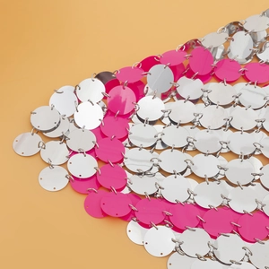 Detalle de lentejuelas plateadas y rosas unidas por aros metálicos para ropa sexy