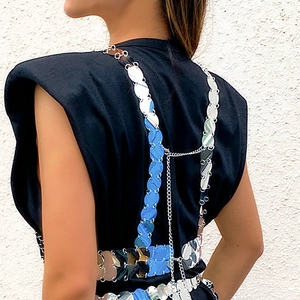 Detail van de achterkant van een zwarte top met zilveren en blauwe metalen schijf-lichaamskettingen