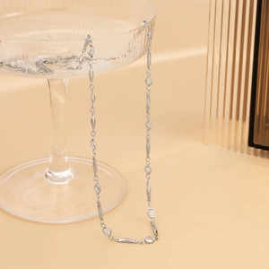 Elegant silver body chain with geometric crystals and polished metal on glass tray