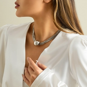 Detail van de meerlaagse zilveren ketting met een grote gepolijste metalen bolhanger