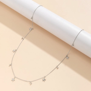 Minimalistische silberne Körperkette mit Sternanhängern und Strass auf weißem Sockel