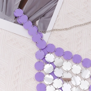 Dettaglio macro di paillettes tonde viola e argento su una catena per il corpo in metallo