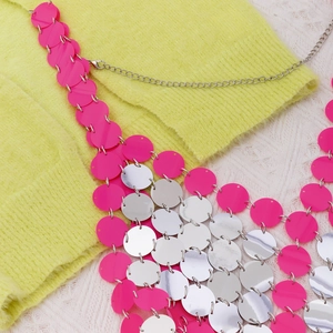Dettaglio macro di catena per il corpo con paillettes rosa e argento su maglia gialla