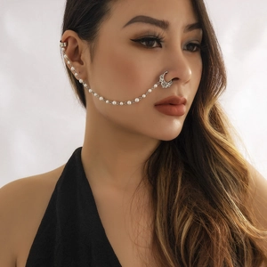 Detail of silver crescent moon nose ring connected to ear clip with faux pearl chain
