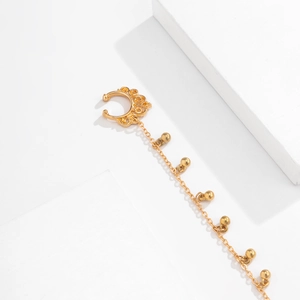 Detailed view of punk style gold nose ring with a long tassel chain and small gold beads
