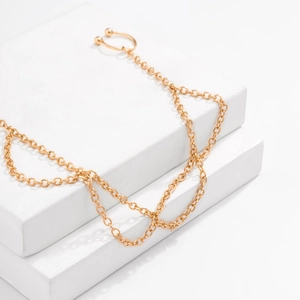 Detail of gold layered chain earring featuring a polished metal hoop on white background