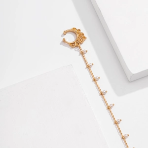 Detail of golden nose ring with delicate chain and white pearls on white stone