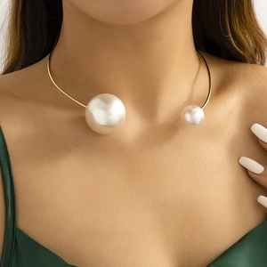 Close-up of a gold metal choker with asymmetric white pearls worn by a fashion model