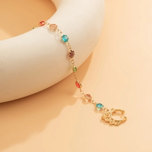 Detail of gold chain nose ring featuring colorful faceted gemstones and cutout C-ring
