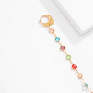 Macro detail of golden nose ring chain with multi-color rhinestones and boho hollow design