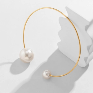 Detailed macro view of asymmetric white pearls on a polished gold-plated metal choker