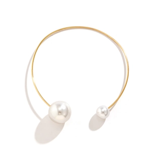 Macro detail of asymmetric faux pearl ends on a golden minimalist metal choker necklace