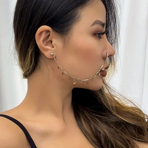 Detail of gold star pendants on a nose-to-ear chain jewelry worn by a female model
