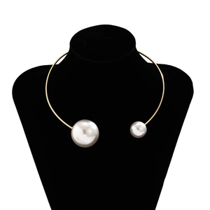 Detail view of gold metal choker with asymmetric white faux pearls on black mannequin