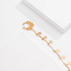 Detail of gold star tassel chain ear cuff with intricate hollow swirl patterns