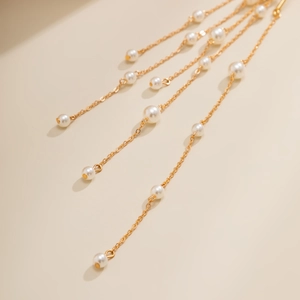Detailweergave van de elegante lange gouden kwastjes ketting met fijne parel accenten