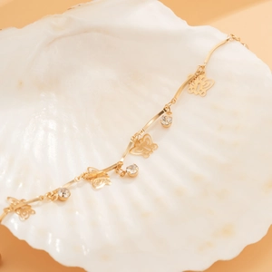 Gold butterfly link bracelet with clear zircons displayed on a white shell prop