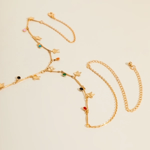 Detail view of gold body chain with colorful enamel dots and star charms